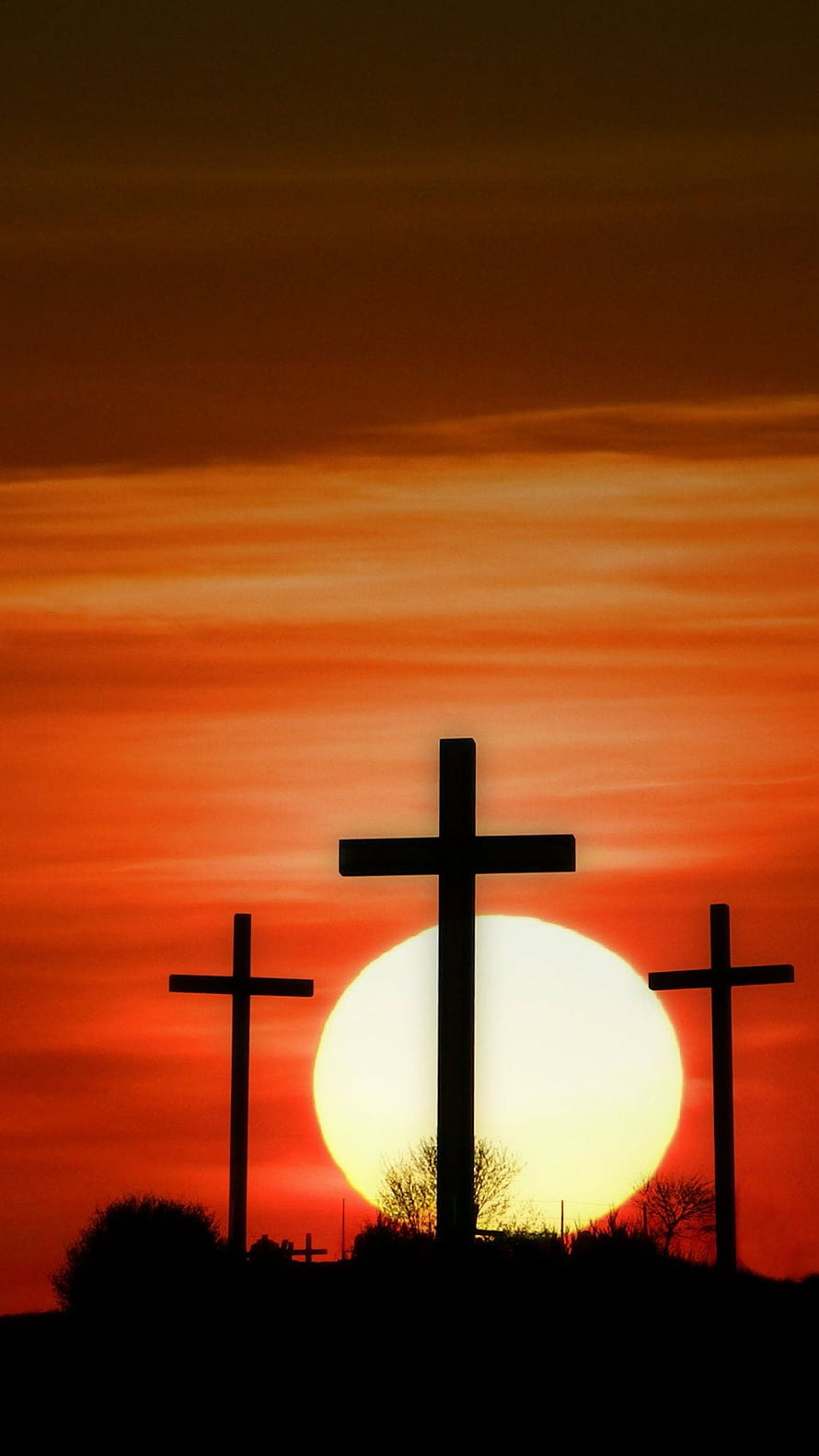 Three Silhouetted Crosses Against a Vibrant Orange Sunset Sky HD phone wallpaper
