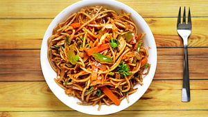 Street Style Veg Chowmein with Carrots and Peppers in a White Bowl on Wooden Table HD wallpaper
