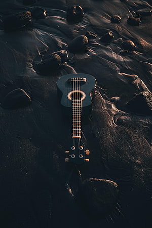 Black Ukulele Resting on Wet Sand and Rocks at a Dark Beach HD phone wallpaper