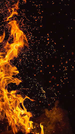 Vibrant Bonfire Flames and Rising Embers Against a Dark Night Sky HD phone wallpaper