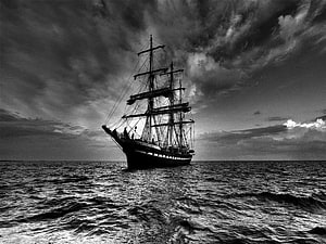 Monochromatic Tall Ship Sailing on Open Ocean Under Dramatic Stormy Skies HD wallpaper