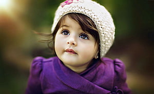 Adorable Toddler Girl in Purple Coat and White Knit Hat Looking Up HD wallpaper