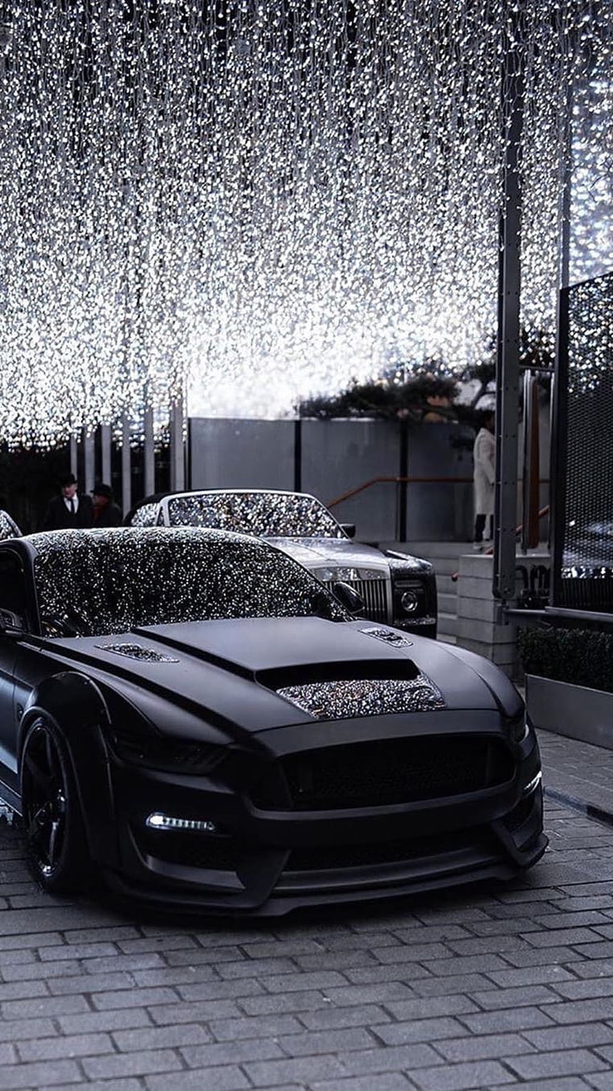Matte Black Ford Mustang GT with Hood Scoop Parked Under Glittering Light Installation HD phone wallpaper