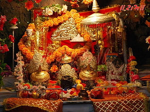 Traditional Hindu Shrine Decorated with Golden Statues and Marigold Garlands HD wallpaper