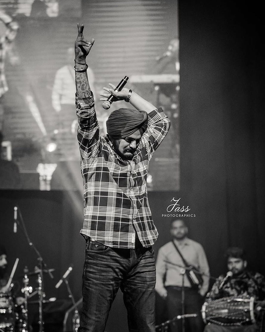 Diljit Dosanjh performing live on stage in a plaid shirt and turban, black and white concert photography HD phone wallpaper