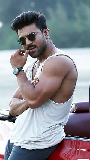Ram Charan in White Tank Top and Round Sunglasses Leaning Against Red Car HD phone wallpaper