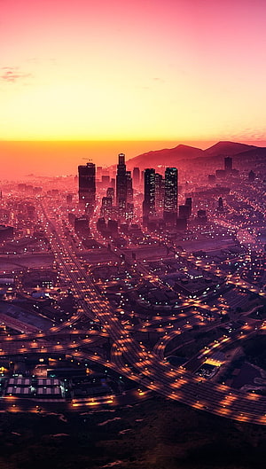 GTA V Los Santos City Skyline at Sunset with Glowing Highway Interchanges and Distant Mountains HD phone wallpaper