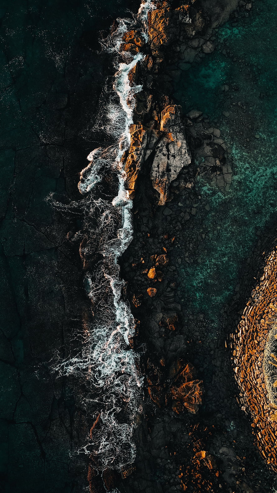 Aerial View of Turquoise Waves Crashing Against Dark Rocky Coastline HD phone wallpaper