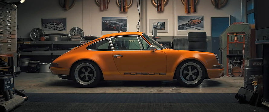 Classic Orange Porsche 911 in a Vintage Garage with Racing Posters and Tools HD wallpaper
