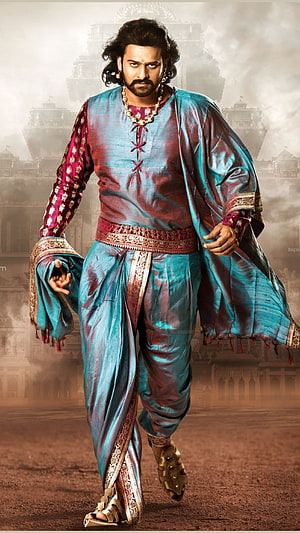 Prabhas in vibrant blue and red traditional royal attire walking forward with a palace background HD phone wallpaper