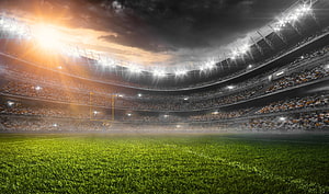 American Football Stadium Interior at Sunset with Bright Floodlights and Full Crowd HD wallpaper