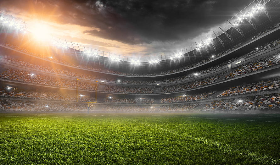 American Football Stadium Interior at Sunset with Bright Floodlights and Full Crowd HD wallpaper