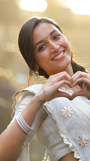 Trisha Krishnan smiling in white traditional outfit making heart gesture HD phone wallpaper