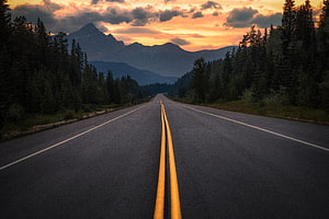 Endless Highway Stretching Toward Majestic Mountains at Golden Sunset HD wallpaper