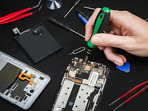 Mobile Phone Repair Technician Using Screwdriver on Circuit Board HD wallpaper