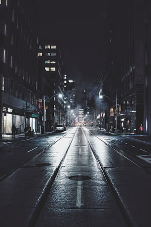 Moody Nighttime City Street with Wet Pavement and Tram Tracks HD phone wallpaper