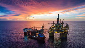 Offshore Oil Rig and Supply Vessel at Sunset Over the Open Ocean HD wallpaper