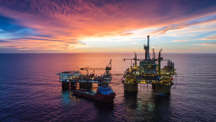 Offshore Oil Rig and Supply Vessel at Sunset Over the Open Ocean HD wallpaper
