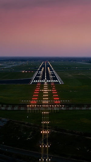 Illuminated Airport Runway at Dusk with Pink Sky and Approach Lighting System HD phone wallpaper