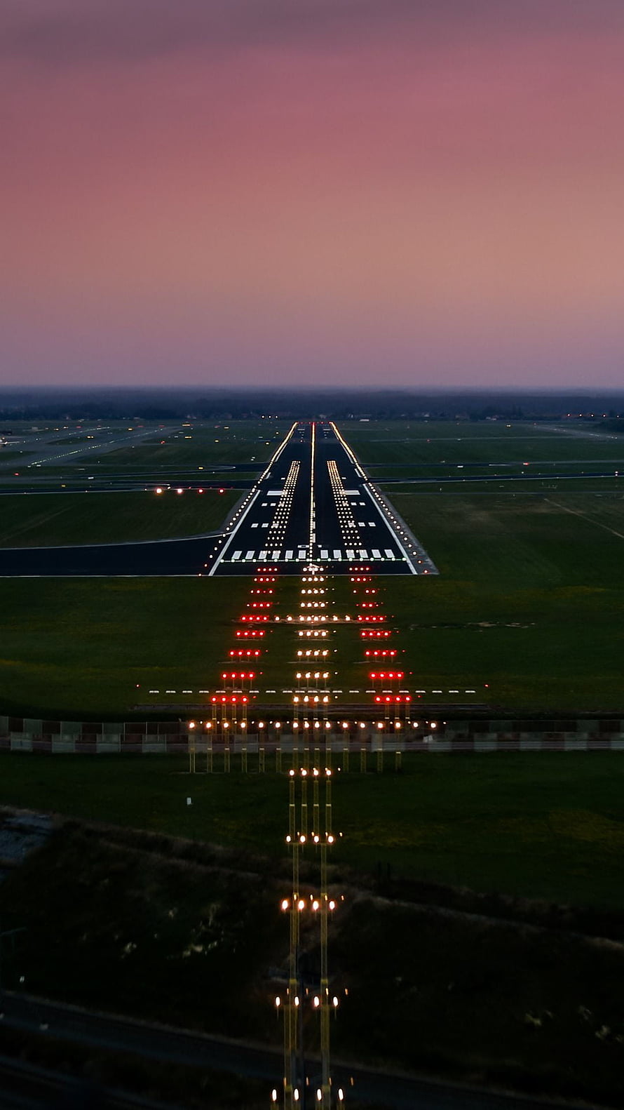 Illuminated Airport Runway at Dusk with Pink Sky and Approach Lighting System HD phone wallpaper