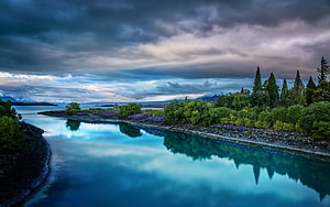 Serene Lake Wakatipu Reflections with Snowy Mountains and Stormy Sky HD wallpaper
