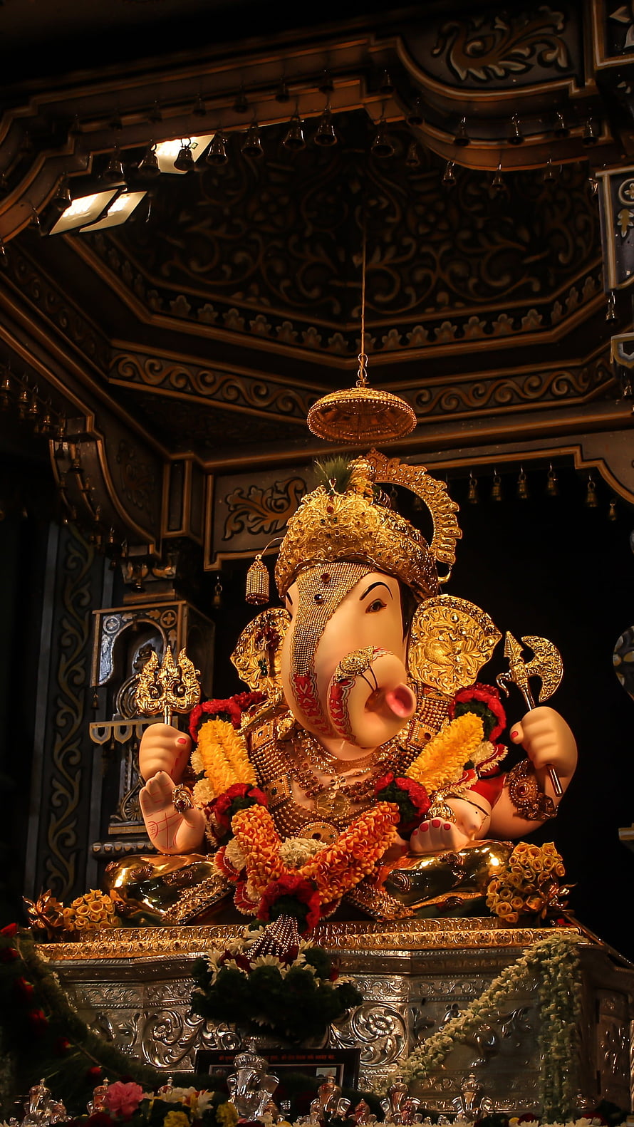 Ornate Golden Ganesha Statue in Temple with Floral Garlands and Intricate Carvings HD phone wallpaper