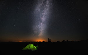 Glowing Green Tent Under the Milky Way Galaxy in a Mountainous Night Landscape HD wallpaper