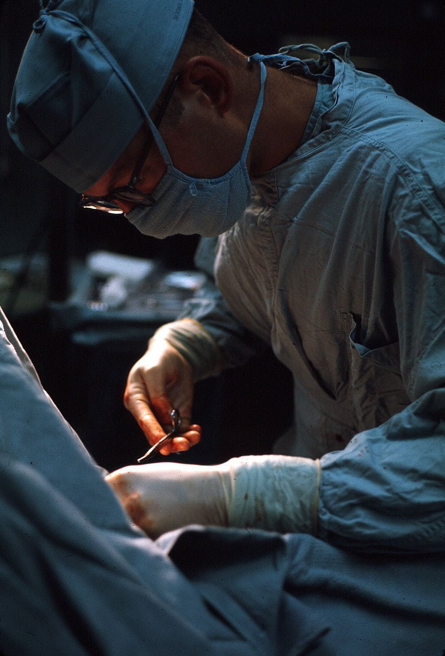Surgeon performing surgery in a field hospital operating room HD phone wallpaper