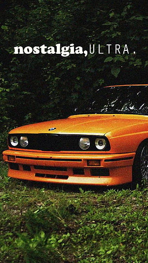 Classic Orange BMW M3 E30 Front View Parked on Grass with Nostalgic Text Overlay HD phone wallpaper