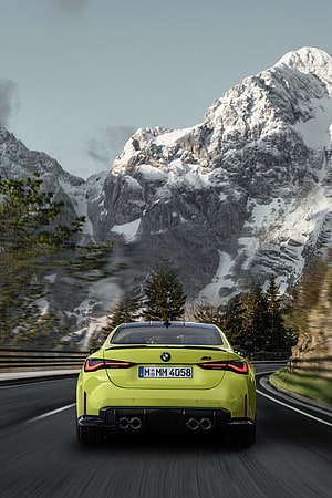 Lime Green BMW M4 Competition Driving on Mountain Road with Snowy Peaks HD phone wallpaper