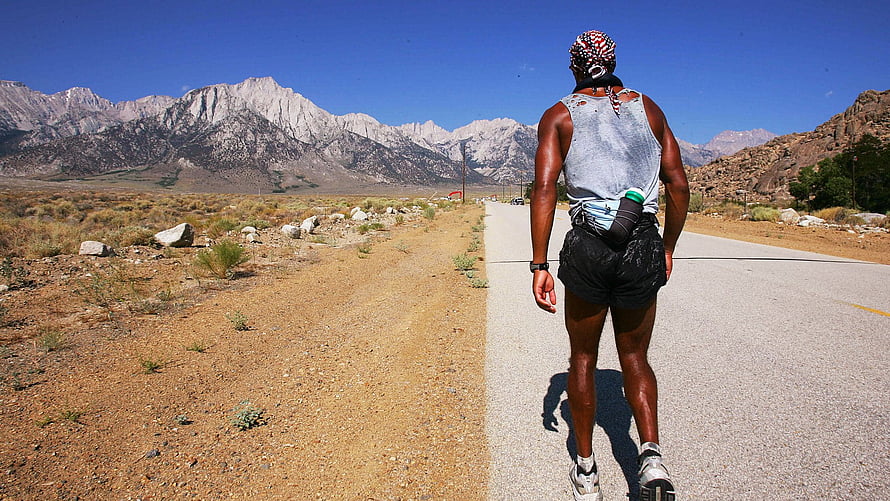 David Goggins Running on a Desert Road with Mountain Range in the Background HD wallpaper