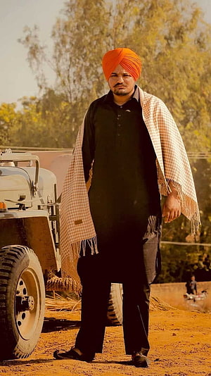 Portrait of a man wearing an orange turban and black kurta standing beside a tractor in a rural field, Sidhu Moose Wala, Village, Background HD phone wallpaper