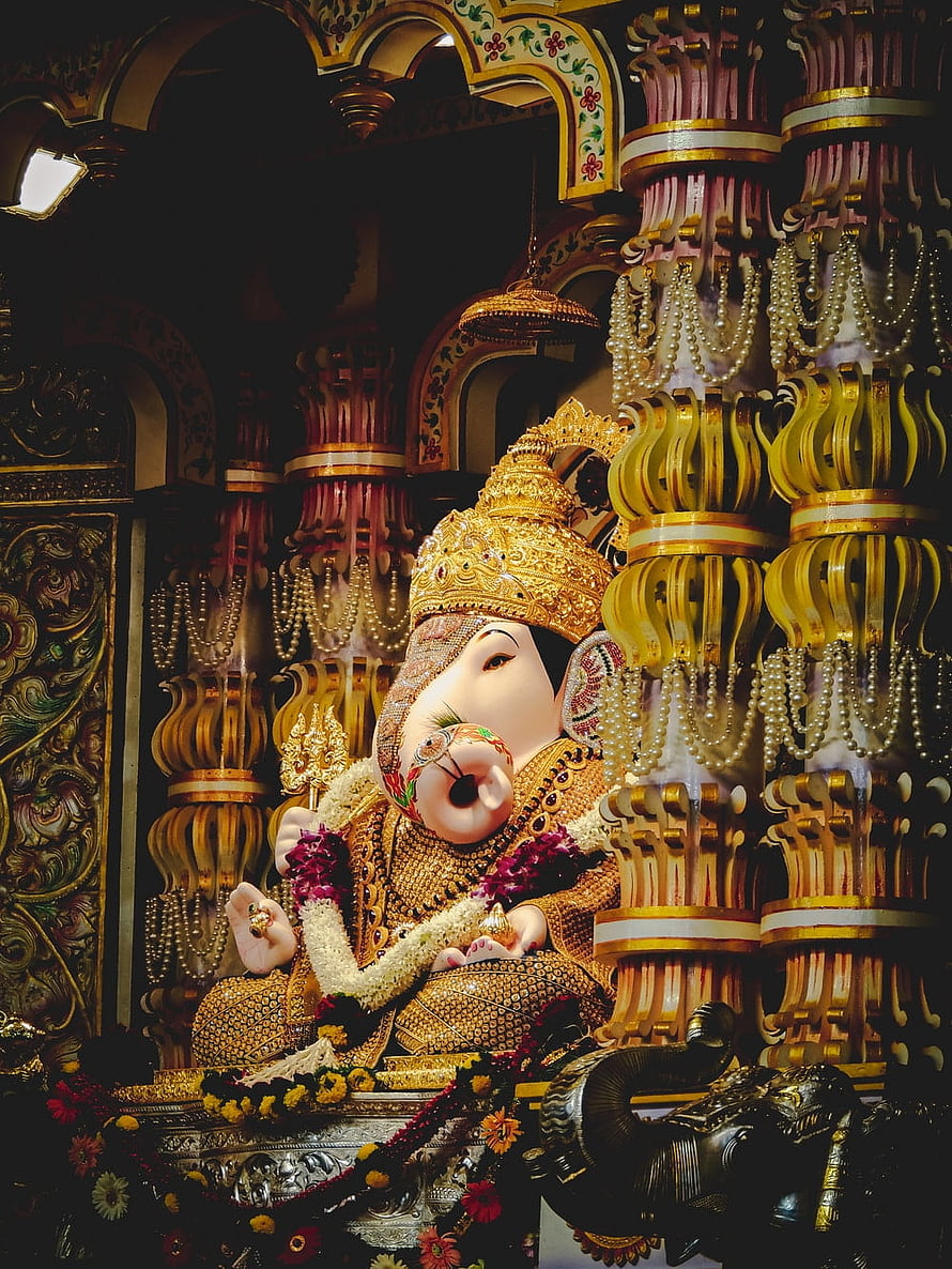 Ornate Golden Ganesha Statue in Temple with Intricate Pillars and Floral Garlands HD phone wallpaper