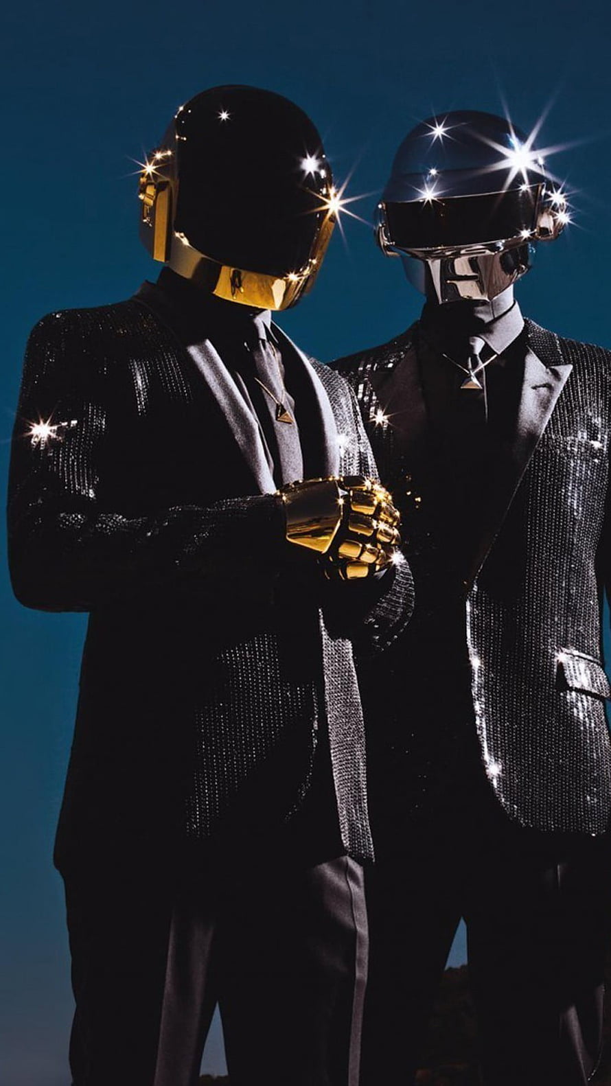 Daft Punk in Iconic Chrome and Gold Helmets Wearing Sequined Suits Against a Deep Blue Sky HD phone wallpaper