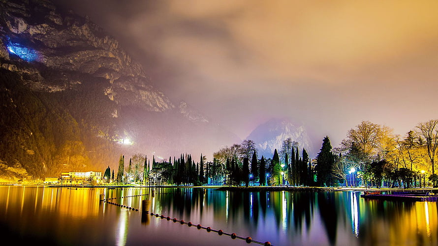 Misty Mountain Lake at Night with Warm City Lights and Reflections HD wallpaper