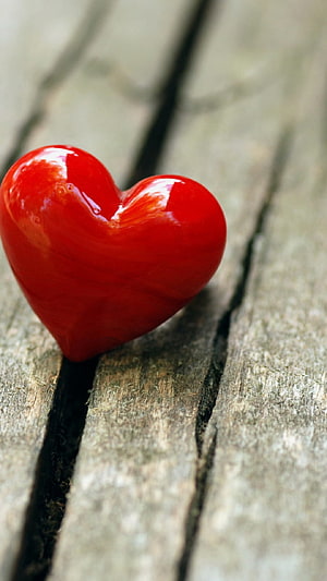Glossy Red Heart Ornament Resting on Weathered Wooden Planks HD phone wallpaper