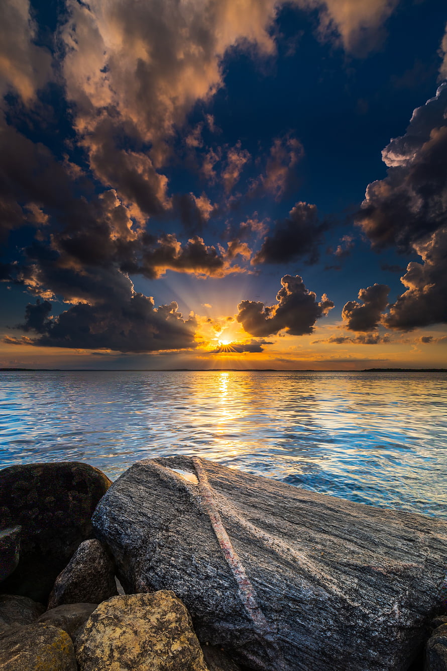 Golden Sunburst Breaking Through Dramatic Clouds Over a Calm Lake at Dawn HD phone wallpaper