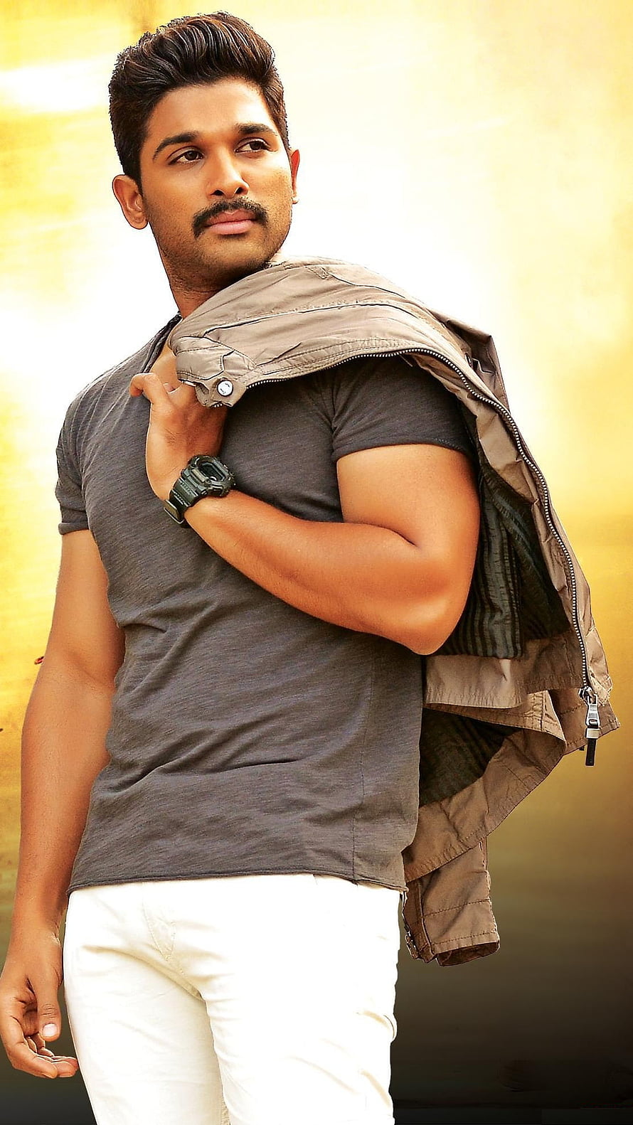 Allu Arjun in a grey t-shirt and white trousers with a jacket draped over his shoulder HD phone wallpaper