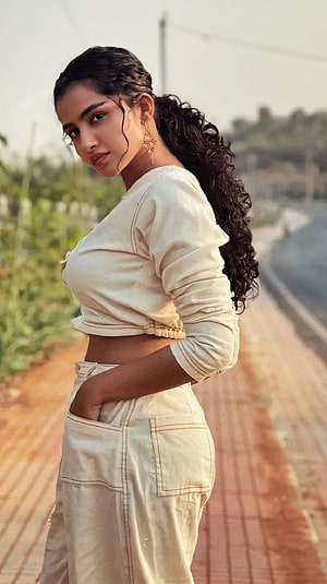 Anupama Parmeshwaran in a cream crop top and cargo pants on a rural road HD phone wallpaper