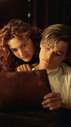 Titanic Film Still of Jack and Rose Examining a Photograph in Warm Candlelight HD phone wallpaper
