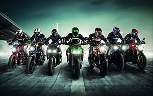 Seven Riders on Sport Motorcycles with Bright Headlights on a City Road at Night HD wallpaper