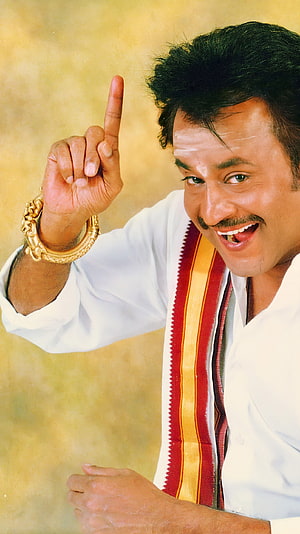 Rajinikanth in traditional white attire with gold bangles and a red and yellow sash HD phone wallpaper