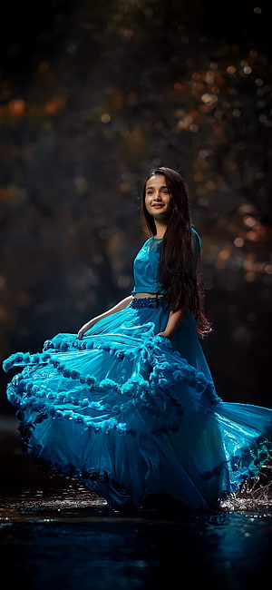 Young woman in flowing turquoise gown standing in shallow water with dark forest bokeh background, Actress, love, kerala, nature, girl, hot, india, mallu, Bollywood HD phone wallpaper