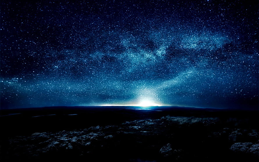 Vast Milky Way Galaxy Arching Over a Dark Rocky Horizon Under a Deep Blue Starry Night Sky HD wallpaper