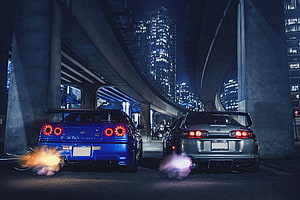 Nissan Skyline GT-R R34 and Toyota Supra MK4 drifting under city overpass at night HD wallpaper