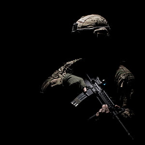 Silhouetted Soldier in Tactical Gear Holding an Assault Rifle Against a Black Background HD phone wallpaper