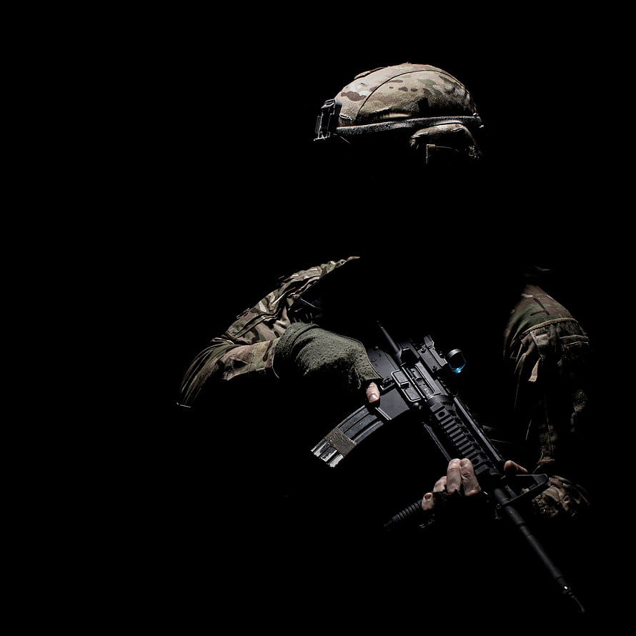 Silhouetted Soldier in Tactical Gear Holding an Assault Rifle Against a Black Background HD phone wallpaper