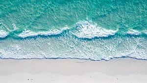 Aerial View of Turquoise Ocean Waves Rolling onto White Sandy Beach HD wallpaper