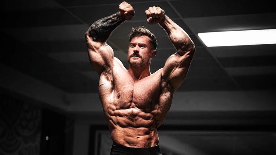 Chris Bumstead Flexing Muscular Physique in Dark Gym Setting HD wallpaper