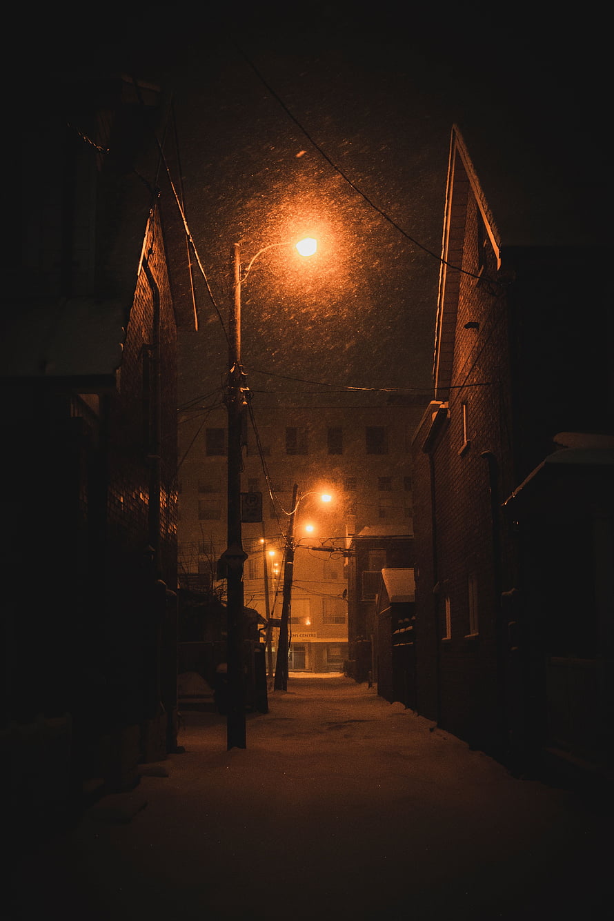 Snowy Urban Alleyway at Night Illuminated by Warm Street Lamps HD phone wallpaper